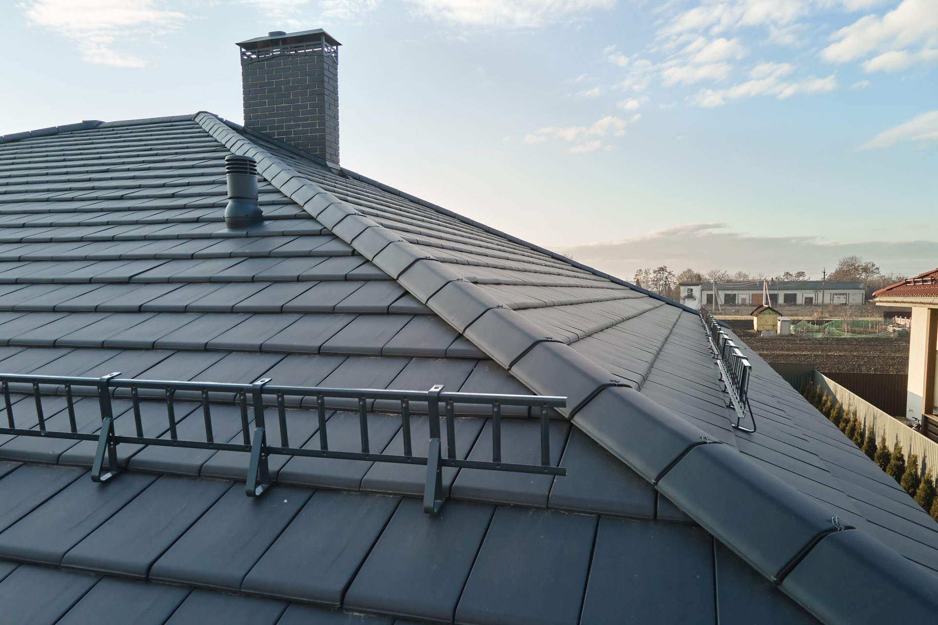 Grey brick chimney stack on a modern tiled house roof